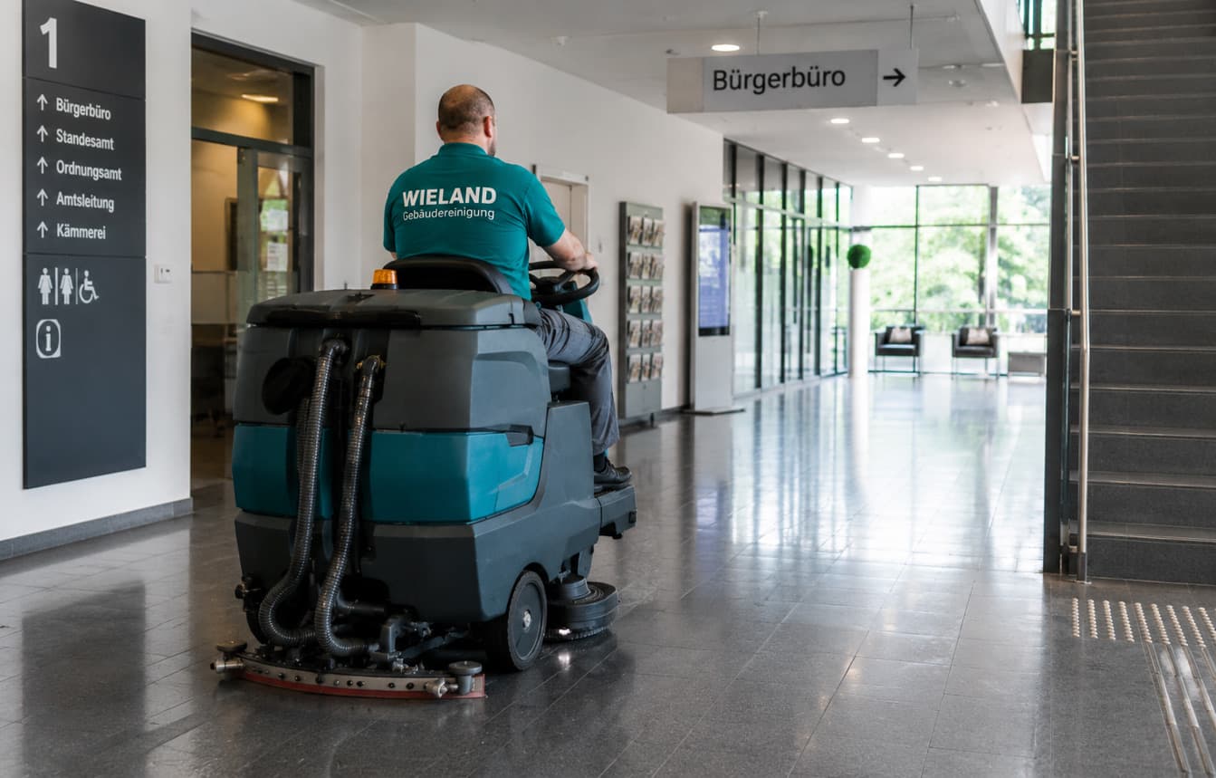 Ride-on scrubber dryer cleaning the floor in the foyer of a public service centre